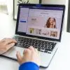 Hands typing on a laptop with an e-commerce website open, showcasing online shopping.