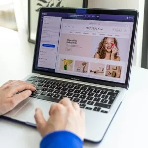 Hands typing on a laptop with an e-commerce website open, showcasing online shopping.