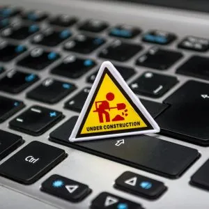 A miniature under construction sign placed on a laptop keyboard symbolizing digital development.