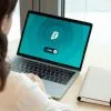 A woman working on a laptop with a VPN icon on screen for secure online browsing.