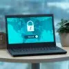 Laptop displaying a security lock icon on a table with a potted plant and clock.