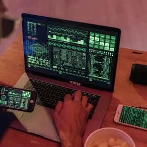 Man working with cybersecurity software on laptop and smartphone.