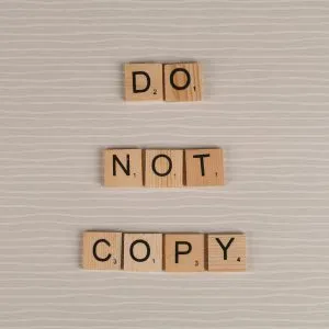 Close-up of wooden tiles spelling 'Do Not Copy' on a textured surface.