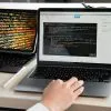 A developer writing code on a laptop, displaying programming scripts in an office environment.
